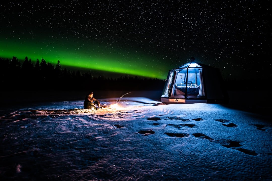 Northern lights aurora borealis over snowy Sami landscape in Lapland with traditional lavvu tent